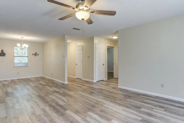 an empty room with windows and fan