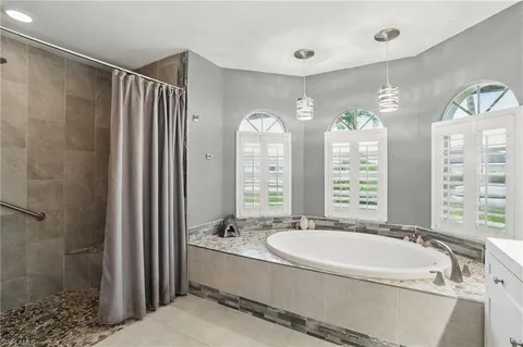 a bathroom with a granite countertop tub sink and mirror