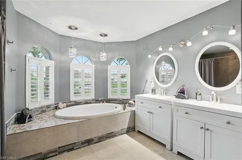 a spacious bathroom with a double vanity sink a mirror and a bathtub