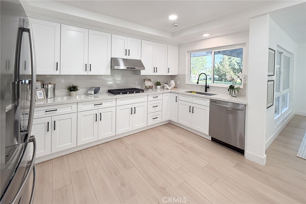 2225 Terraza Place Fullerton, CA 92835 - Photo 21 of 73 a large kitchen with stainless steel appliances granite countertop a stove a sink dishwasher and white cabinets with wooden floor