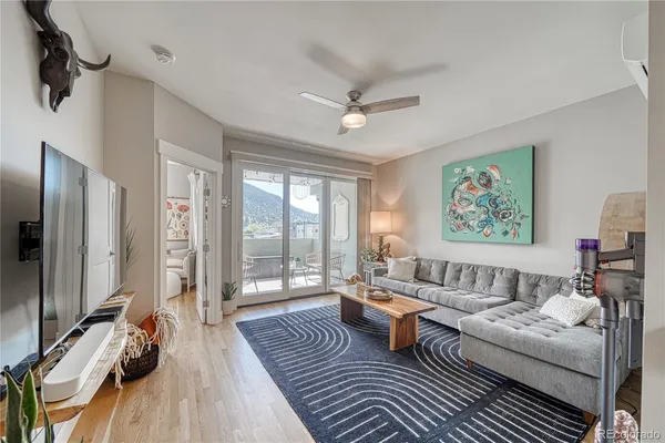 a living room with furniture a large window wooden floor and a rug