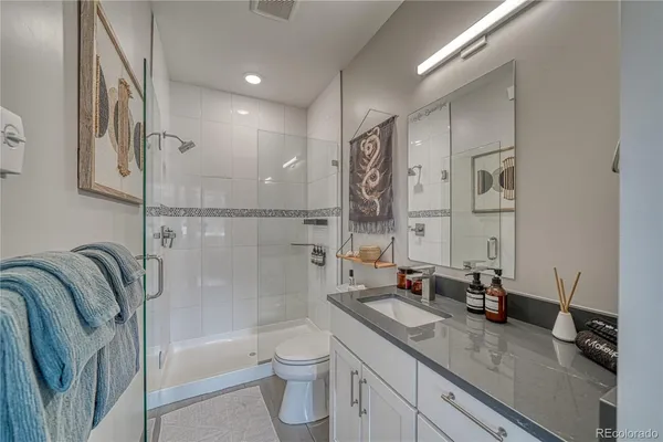 a bathroom with a granite countertop sink a toilet a mirror and shower