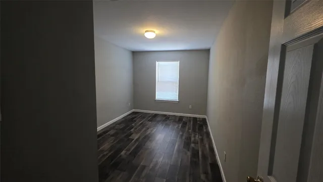 a view of hallway with window and wooden floor