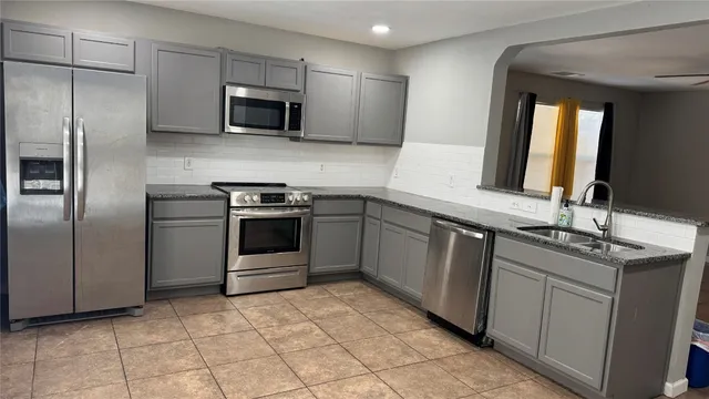 a kitchen with stainless steel appliances granite countertop a stove a sink and a microwave