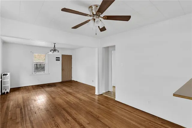 a view of an empty room with window and wooden floor