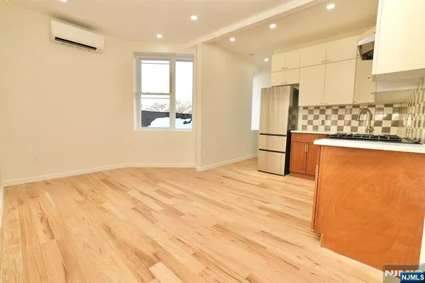 a large white kitchen with stainless steel appliances kitchen island granite countertop a refrigerator and a stove top oven