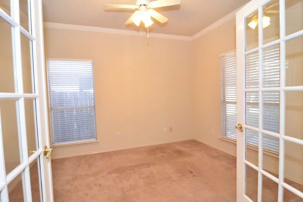 9405 Lightwood Loop Austin, TX 78748 - Photo 12 of 24 French doors open to a neutral room featuring crown molding, two windows with blinds, a ceiling fan with integrated lighting, and carpet flooring