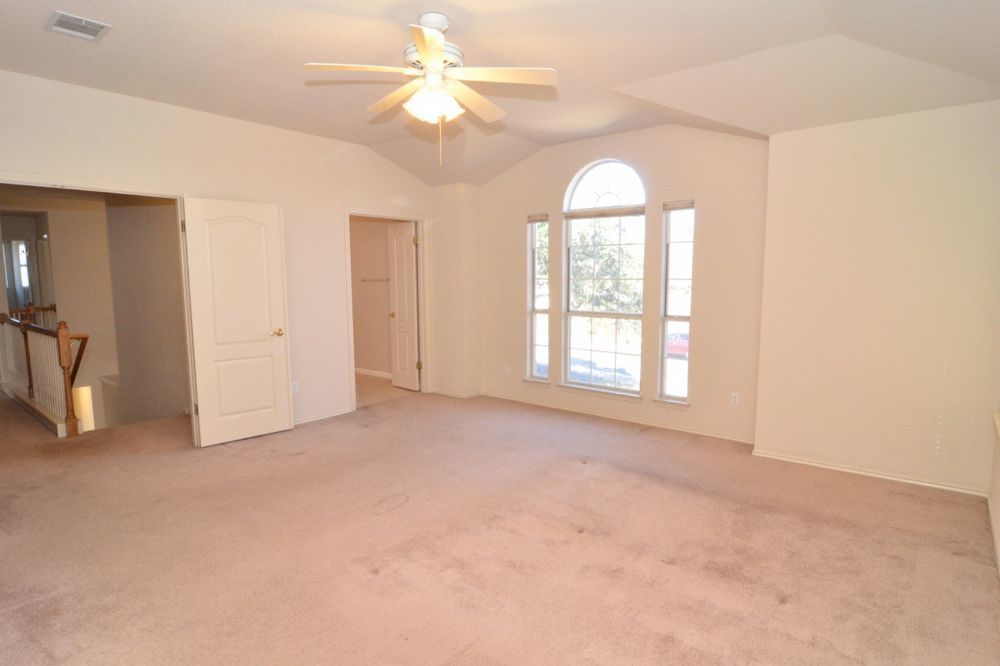 9405 Lightwood Loop Austin, TX 78748 - Photo 23 of 24 Carpeted room featuring a vaulted ceiling with a ceiling fan, arched transom window, and two paneled interior doors