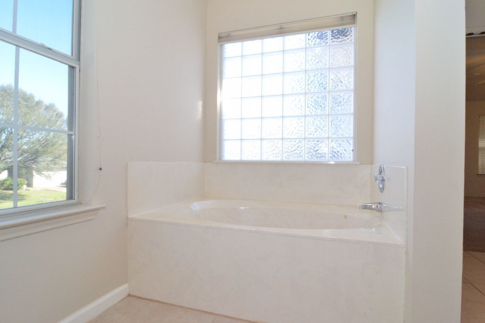 9405 Lightwood Loop Austin, TX 78748 - Photo 24 of 24 Built-in soaking tub with a surrounding deck, complemented by a glass block window and an additional framed window