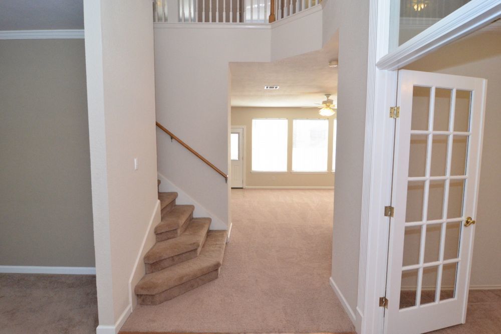 9405 Lightwood Loop Austin, TX 78748 - Photo 8 of 24 Foyer area featuring carpeted stairs with a wood handrail, a French door entry, and crown molding accents
