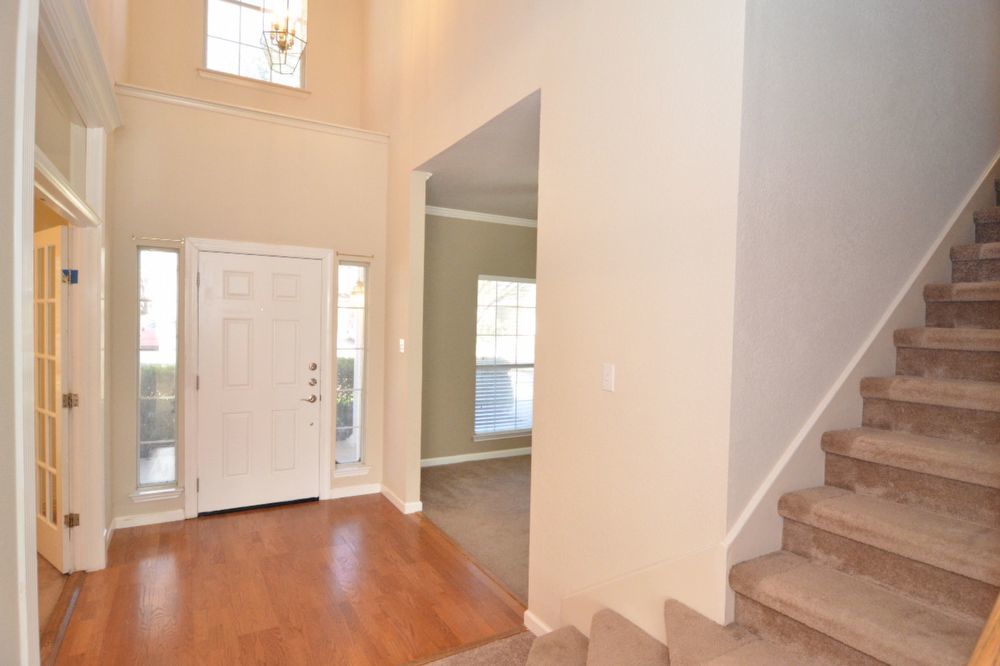 9405 Lightwood Loop Austin, TX 78748 - Photo 10 of 24 Two-story foyer featuring wood-finish flooring, a decorative chandelier, and a paneled front door with sidelights