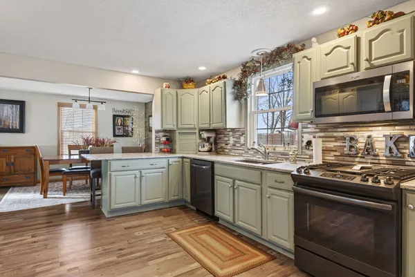 a kitchen with stainless steel appliances granite countertop a stove a sink and a microwave