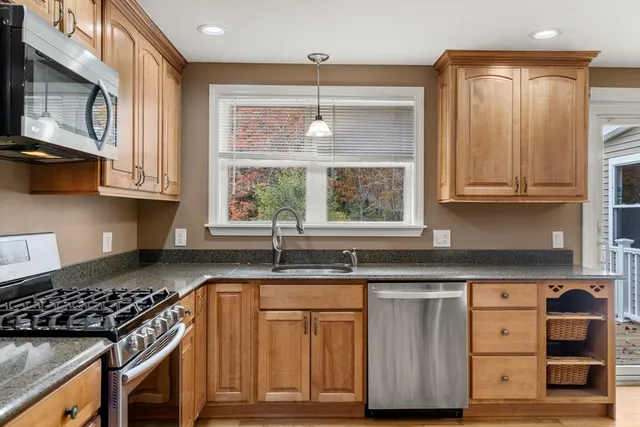 a kitchen with granite countertop a stove a sink and dishwasher with wooden floor