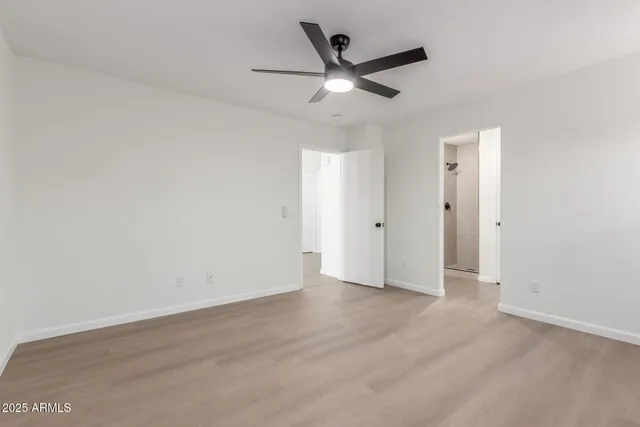 an empty room with wooden floor and a ceiling fan