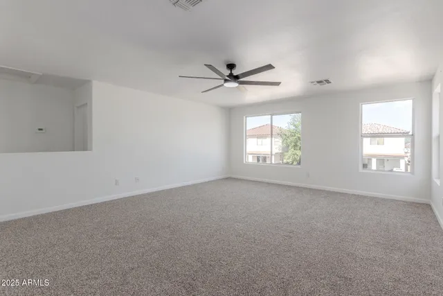 an empty room with windows and ceiling fan