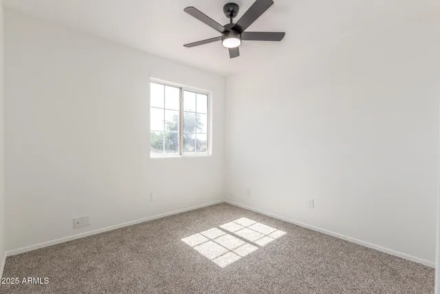 an empty room with a window and a ceiling fan
