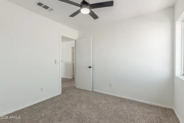 an empty room with a ceiling fan and carpet