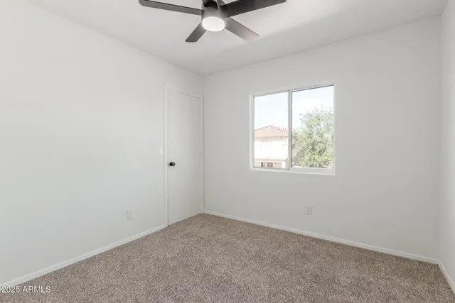 an empty room with a window and a fan