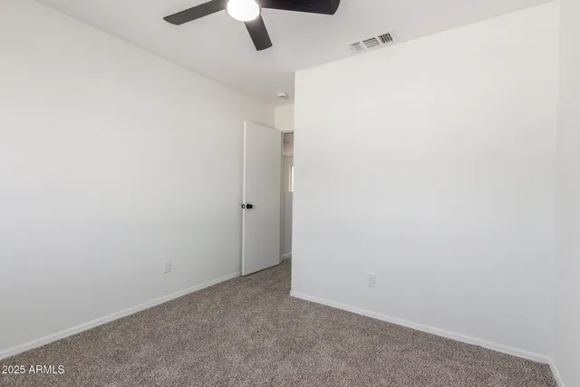 an empty room with a ceiling fan and a window