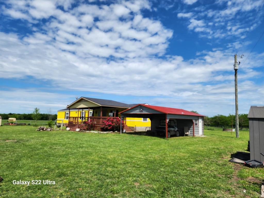 2234 County Road 1056 Celeste, TX 75423 - Photo 2 of 8 Back of house featuring a deck, a lawn, a carport, and an outbuilding