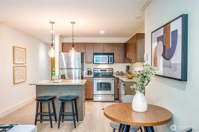 a kitchen with stainless steel appliances granite countertop a dining table chairs and a refrigerator