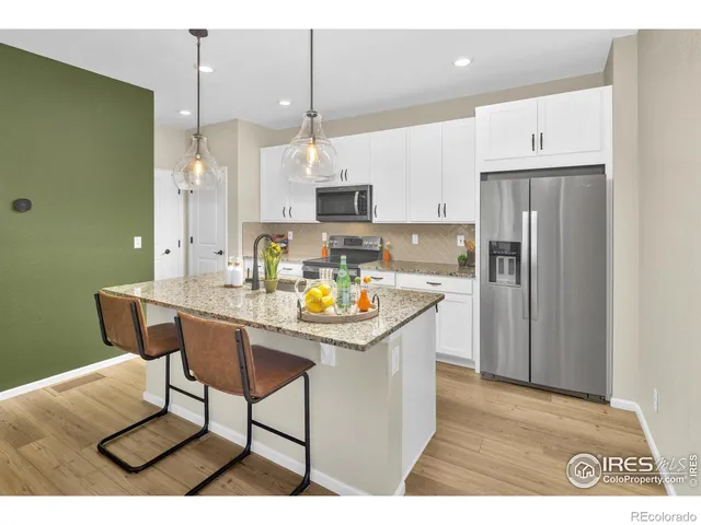 a kitchen with stainless steel appliances kitchen island granite countertop a table chairs and a refrigerator