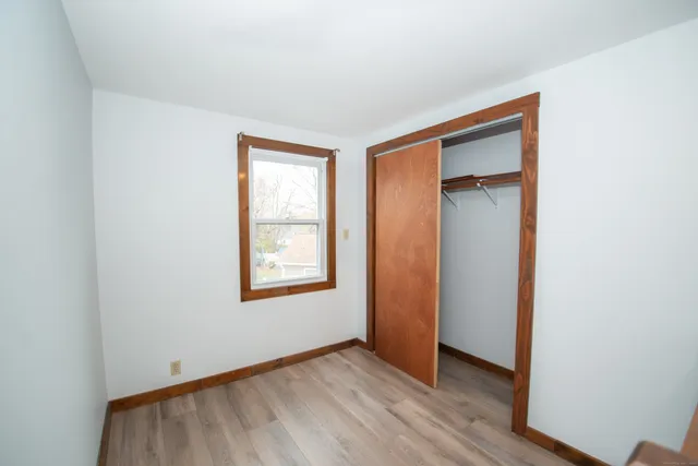an empty room with wooden floor closet and windows