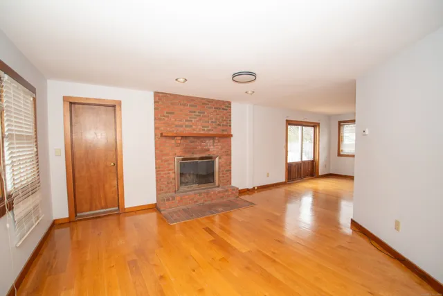 a view of an empty room with a window and fireplace