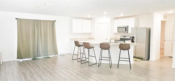 a kitchen with stainless steel appliances a dining table chairs and wooden floor