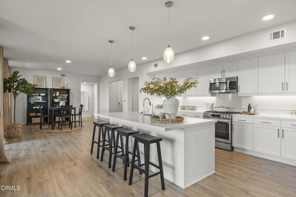 2870 Wagon Wheel Road, Unit 401 Oxnard, CA 93036 - Photo 12 of 49 a kitchen with stainless steel appliances kitchen island granite countertop a table chairs sink and cabinets