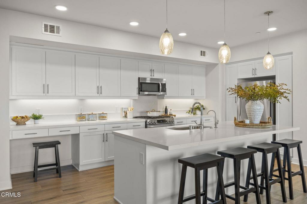2870 Wagon Wheel Road, Unit 401 Oxnard, CA 93036 - Photo 13 of 49 a kitchen with cabinets a sink dishwasher a stove and chairs with wooden floor