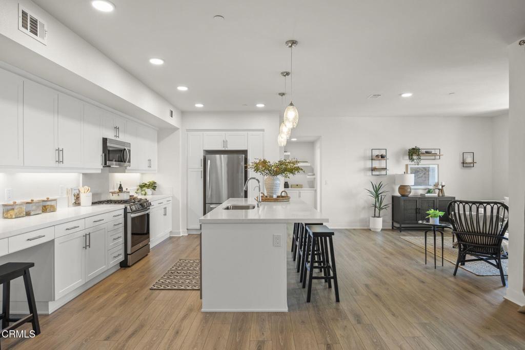2870 Wagon Wheel Road, Unit 401 Oxnard, CA 93036 - Photo 15 of 49 a kitchen with stainless steel appliances kitchen island granite countertop wooden floors and white cabinets