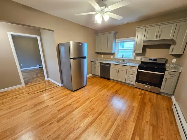 a kitchen with stainless steel appliances kitchen island granite countertop a refrigerator stove top oven and sink