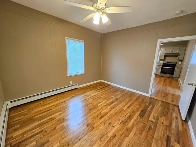 a view of empty room with wooden floor and fan