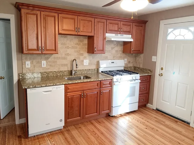 a kitchen with granite countertop wooden cabinets and white appliances