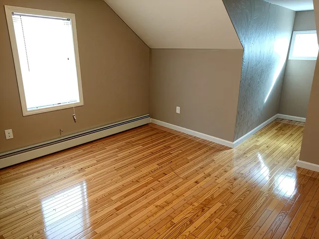 a view of empty room with wooden floor