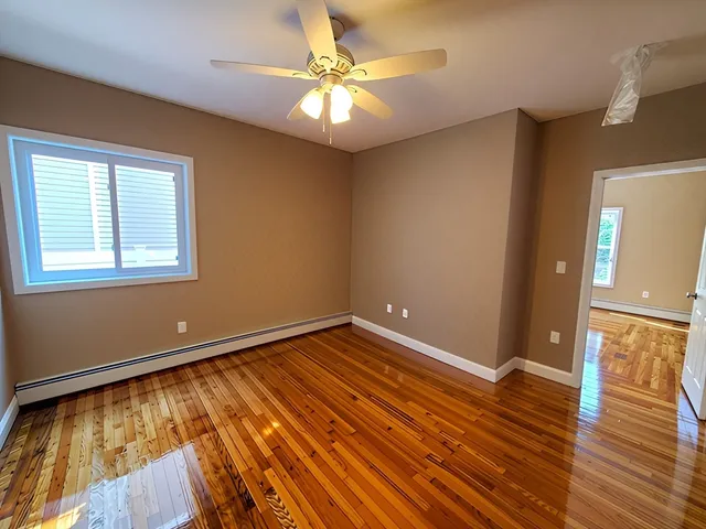 a view of an empty room with window and wooden floor