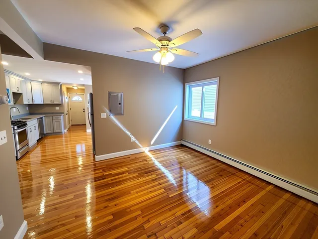 a view of an empty room with window and wooden floor