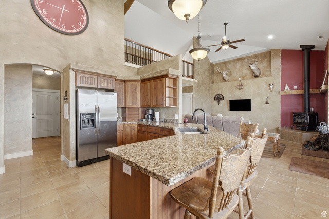 2567 West Rim Rock Drive Stockton, UT 84071 - Photo 9 of 64 Kitchen featuring a granite countertop island with integrated sink, wood cabinetry, stainless steel refrigerator, and tiled flooring