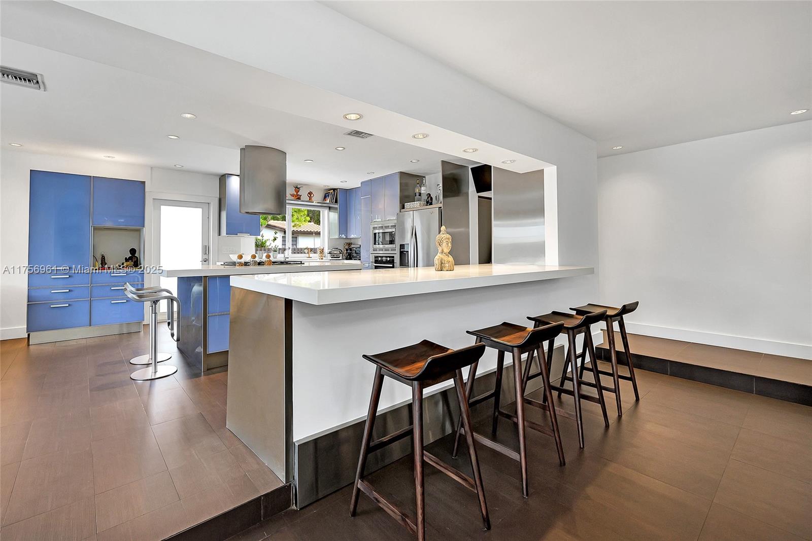 2120 Northeast 204th Street Miami, FL 33179 - Photo 15 of 52 a dining hall with stainless steel appliances granite countertop a stove top oven a dining table and chairs with wooden floor