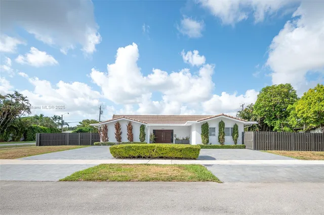 a front view of a house with a yard and potted plants