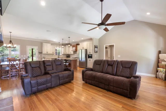 a kitchen with stainless steel appliances granite countertop a dining table chairs refrigerator and microwave