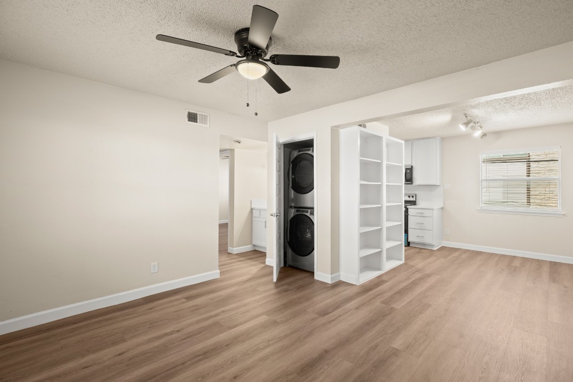 a view of a livingroom with wooden floor a ceiling fan and windows