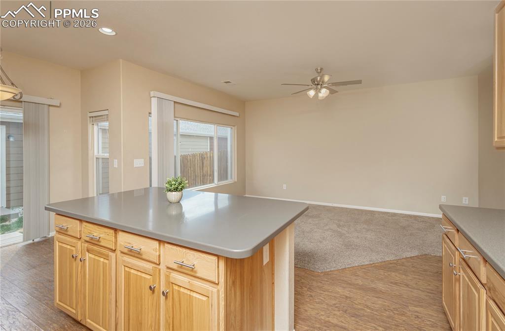 4815 Harrier Ridge Drive Colorado Springs, CO 80916 - Photo 26 of 33 Kitchen featuring light wood finish cabinets, light wood finished floors, a center island, open floor plan, and a ceiling fan