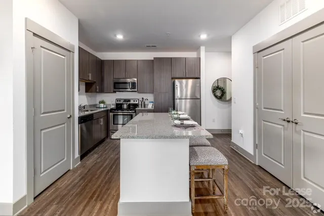 a kitchen with stainless steel appliances granite countertop a refrigerator a stove and a sink with wooden floor