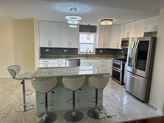 277 Armstrong Drive Buffalo Grove, IL 60089 - Photo 2 of 19 a kitchen with stainless steel appliances granite countertop a sink a stove a refrigerator cabinets and dining table