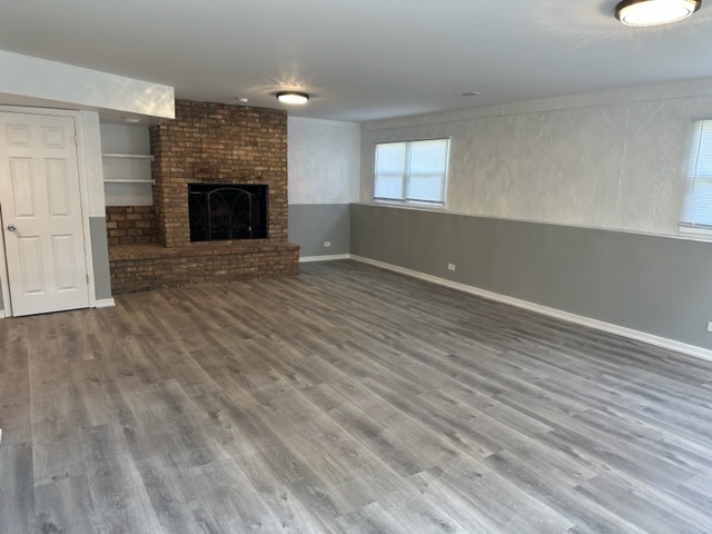 277 Armstrong Drive Buffalo Grove, IL 60089 - Photo 9 of 19 an empty room with wooden floor fireplace and windows