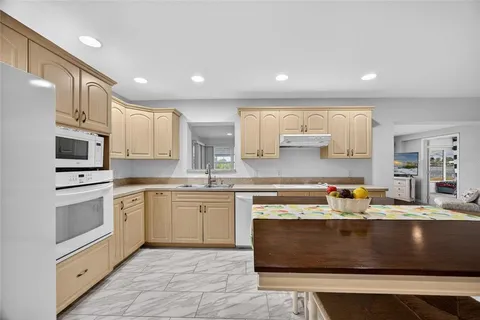a kitchen with kitchen island granite countertop a stove a sink a refrigerator and white cabinets