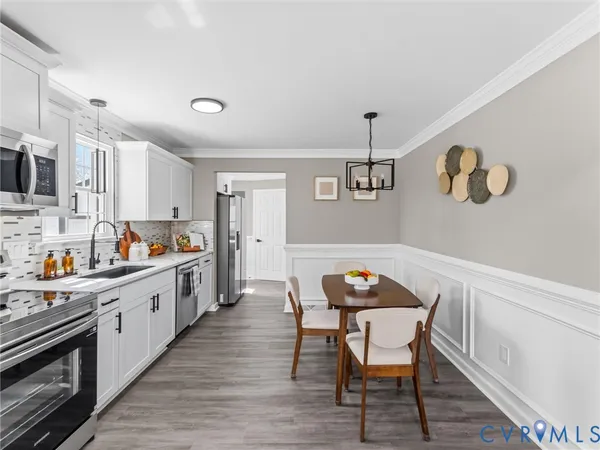 a kitchen with stainless steel appliances a dining table chairs and wooden floor