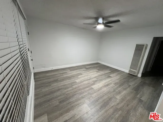 an empty room with wooden floor and fan